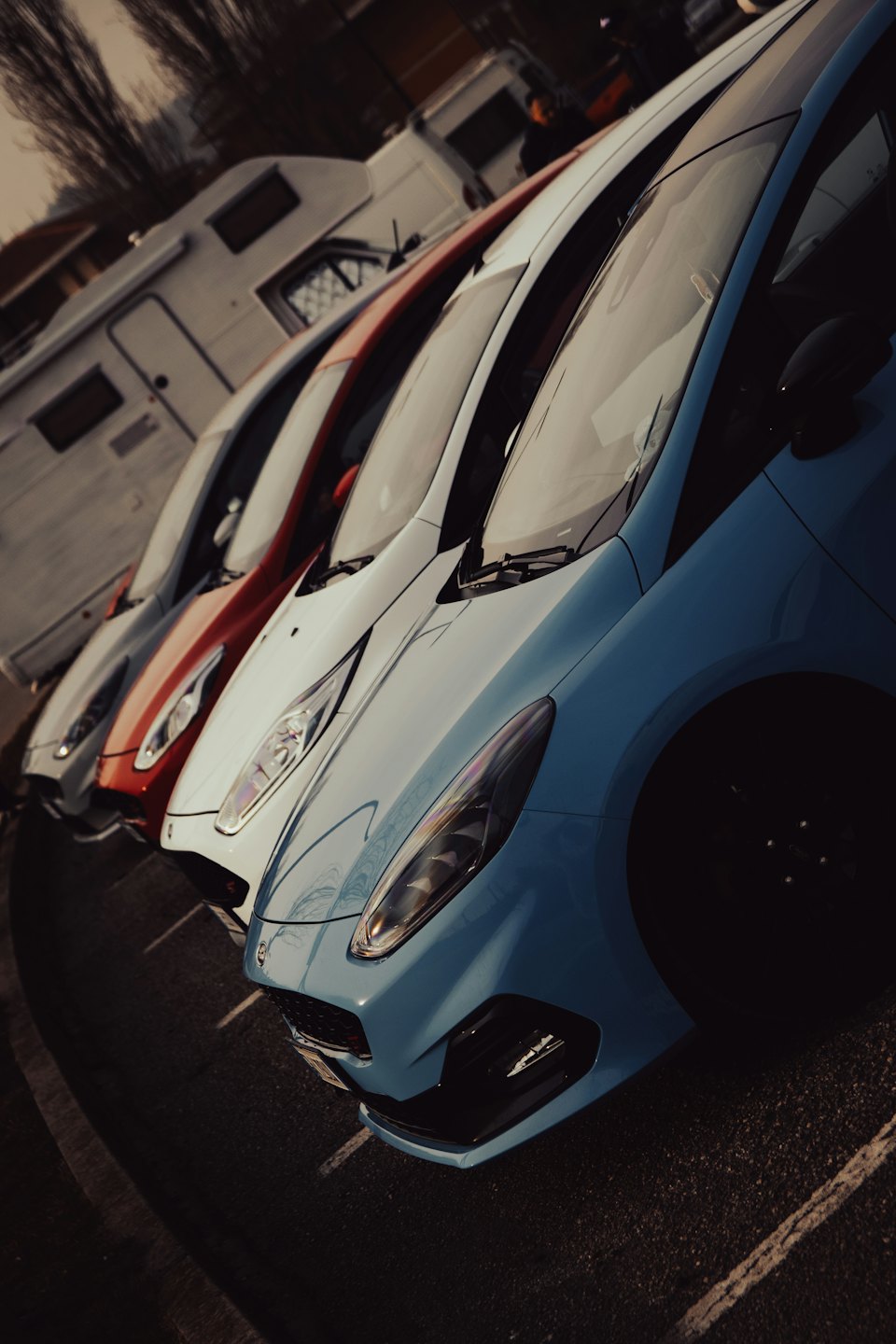 Quattro auto moderne parcheggiate in diagonale in un parcheggio all'aperto.